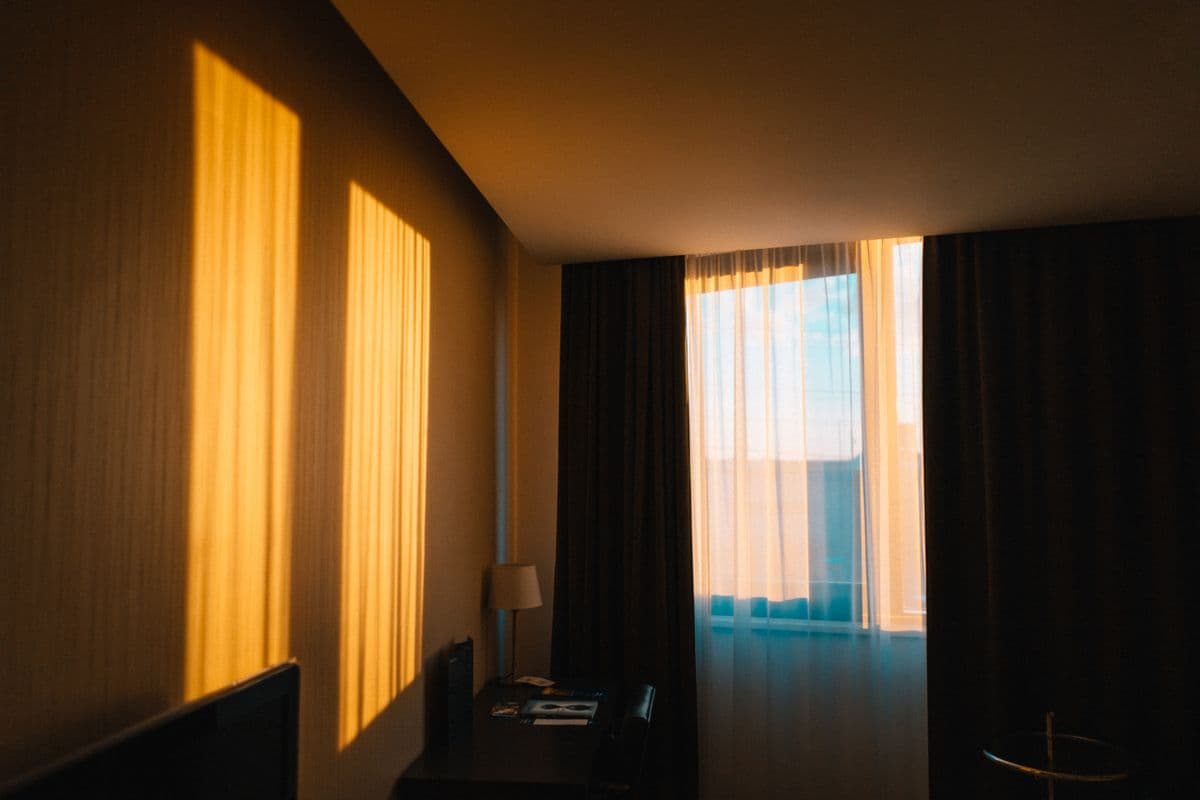 Sinar matahari pagi menyinari interior kamar hotel berkonsep minimalis.