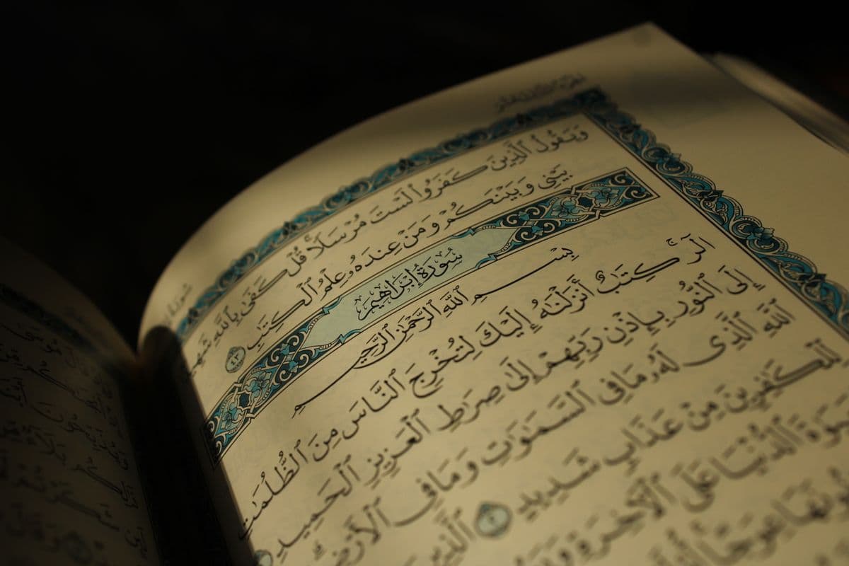 Halaman Al-Quran terbuka dengan pencahayaan hangat menghadirkan kekhusyukan hati