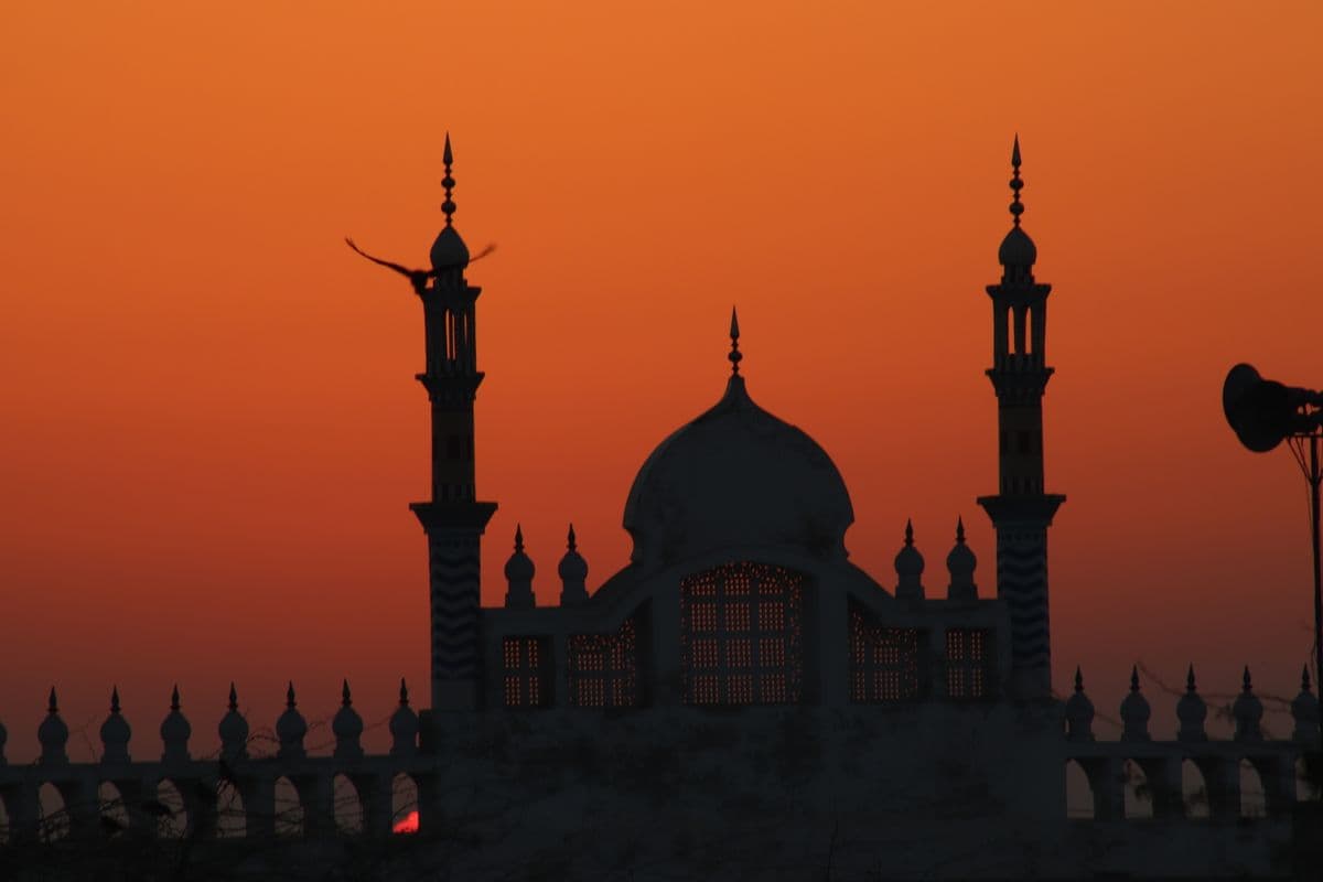 Siluet menara masjid di ufuk barat saat matahari terbenam dengan damai