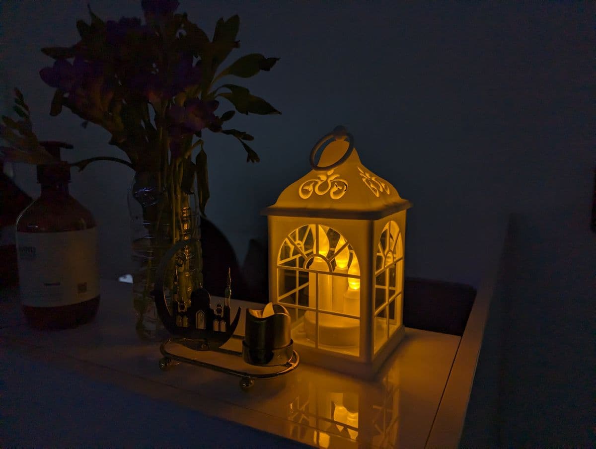 A warm, ambient lantern light in a dark room with Ramadan decoration, creating a cozy atmosphere.