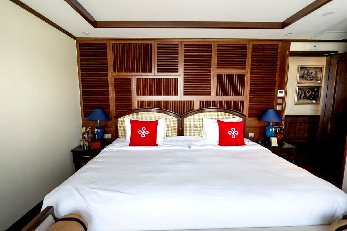 Kamar tidur hotel dengan kasur putih dan bantal merah untuk ilustrasi pakaian ihram