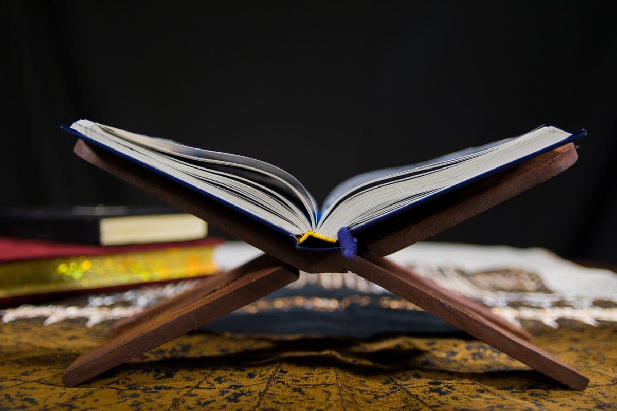 Lembaran ayat suci Al-Qur'an di atas rehal kayu berukir kaligrafi